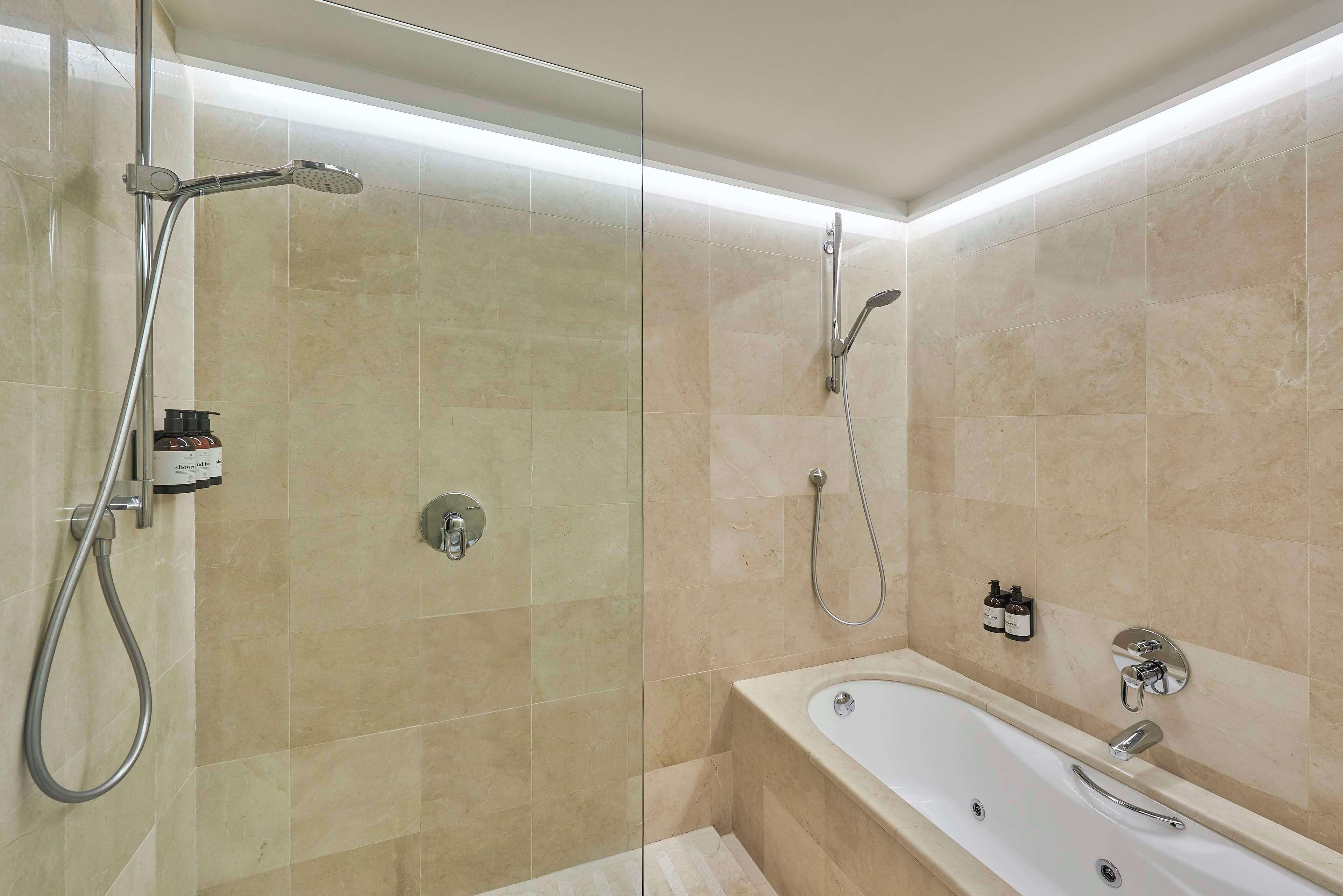 A modern bathroom with a glass-enclosed shower, a freestanding bathtub, and a wall-mounted toilet.