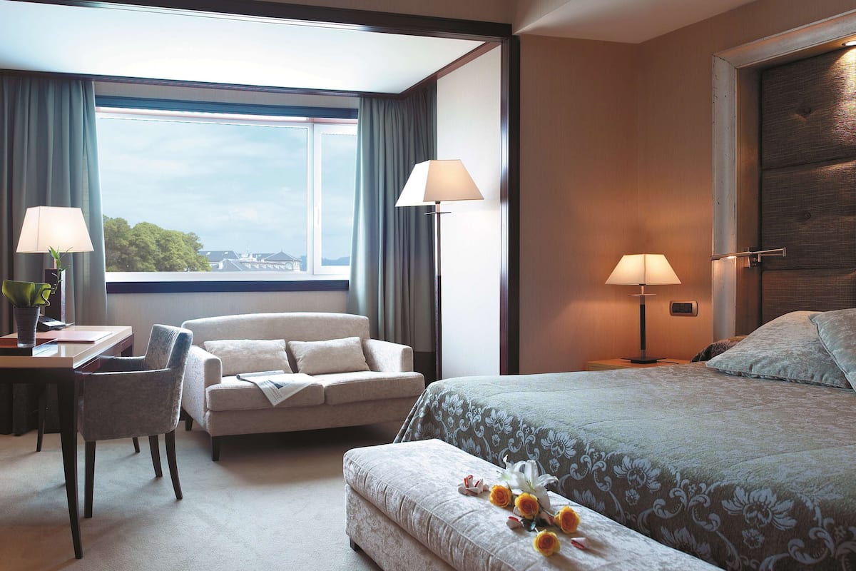 Una habitación de hotel con una cama, un escritorio con una silla, un sofá y dos lámparas.