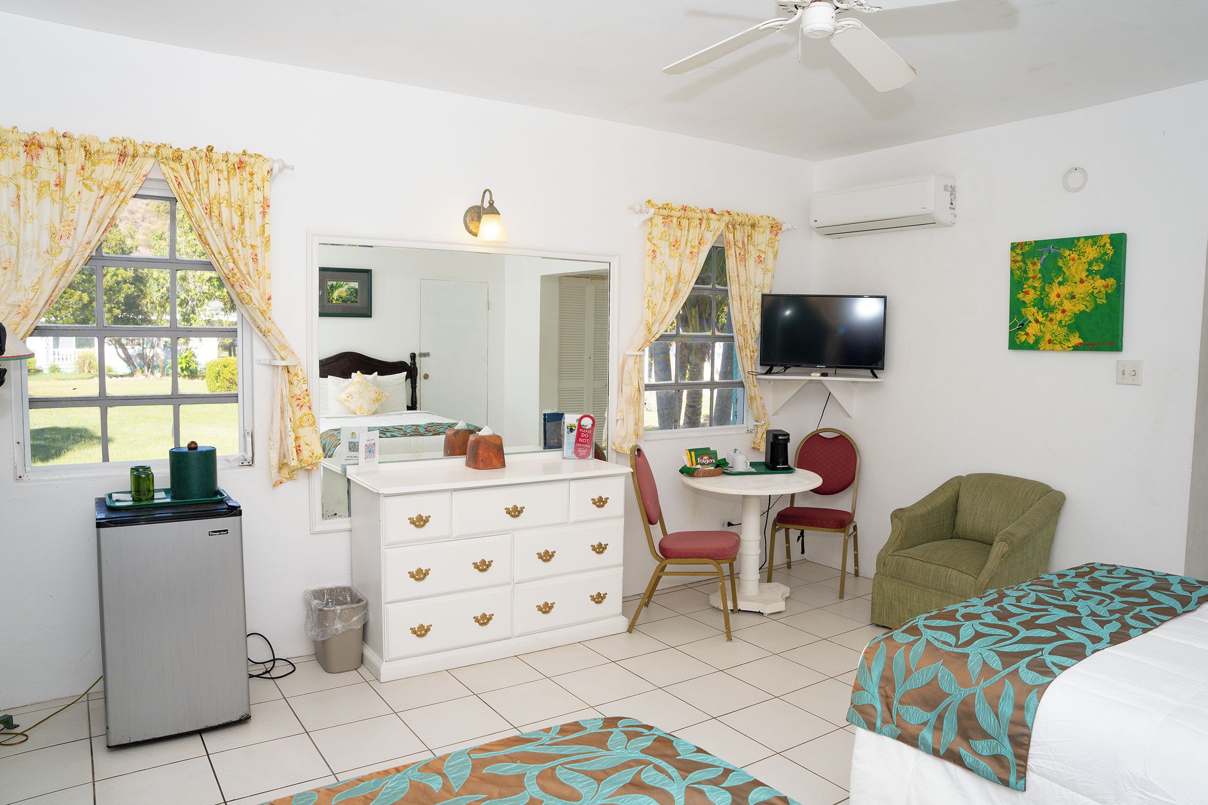 A room with a bed, a desk, a chair, a television, and a refrigerator.