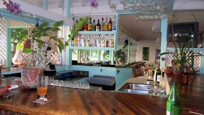 A bar area with a wooden counter, a cash register, and a variety of bottles on shelves. - Oualie Beach Resort (Newcastle)