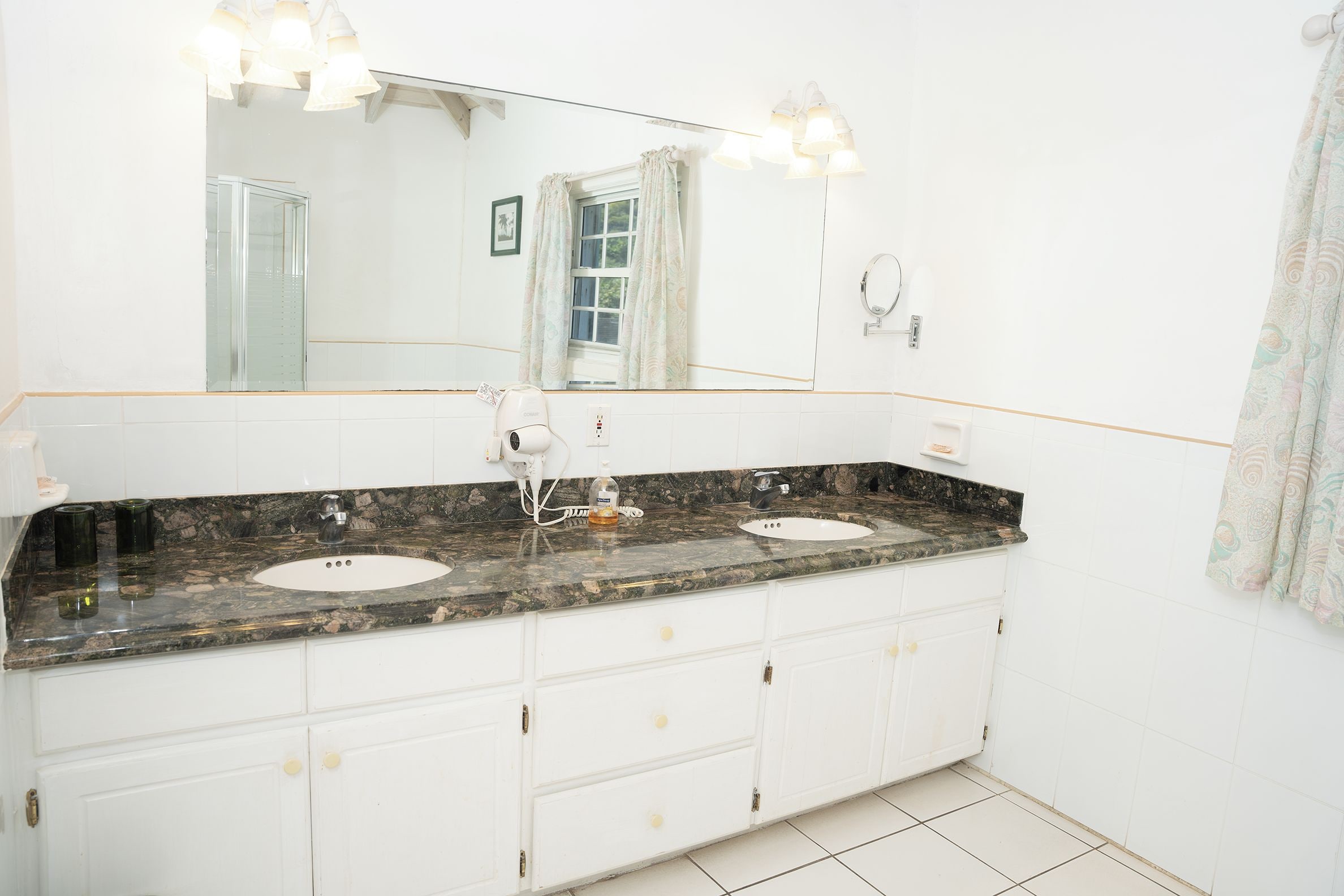 A bathroom with a double sink, a large mirror, and a vanity with drawers.