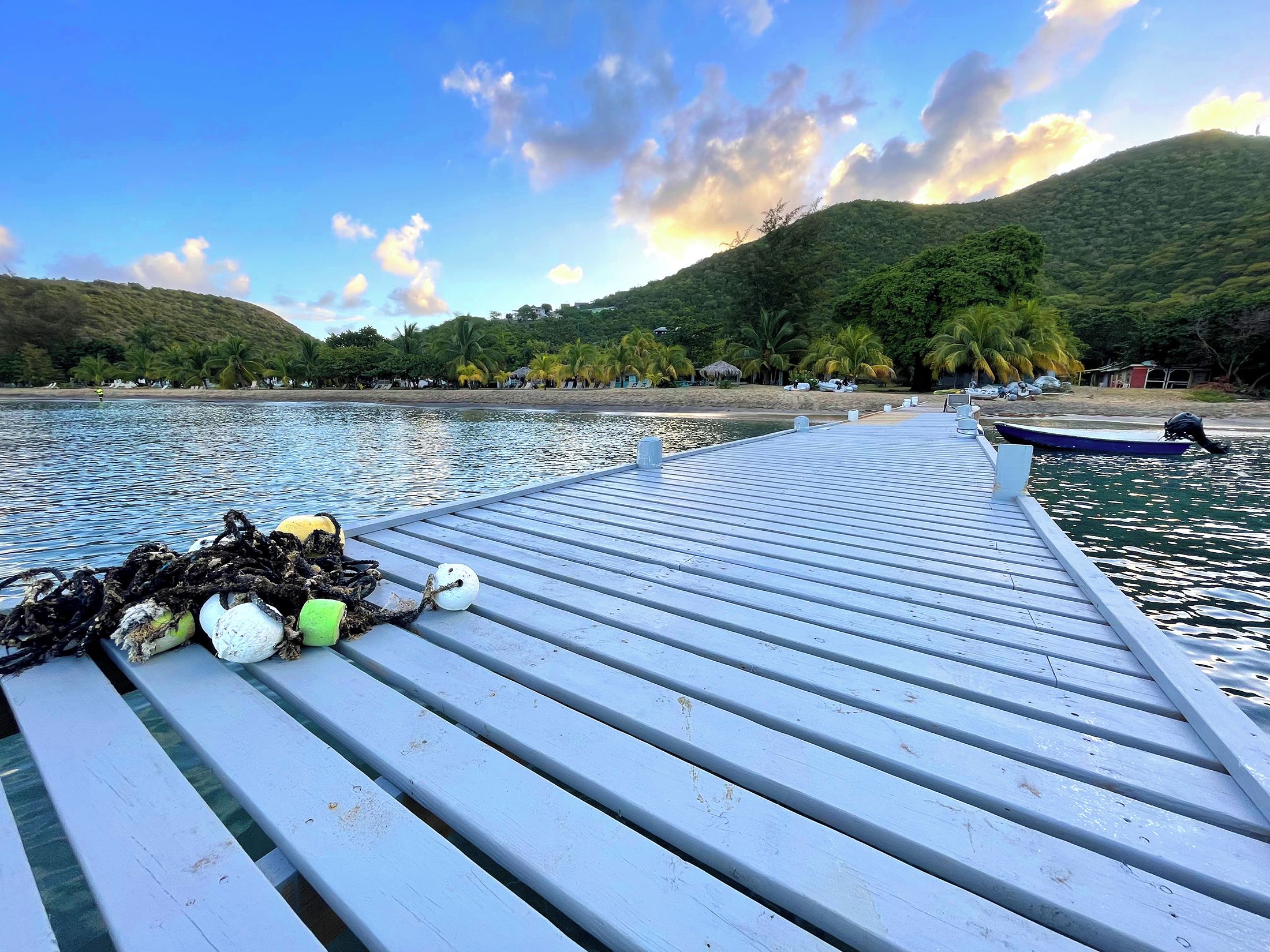 A wooden pier extending into calm waters with a boat docked at the end.