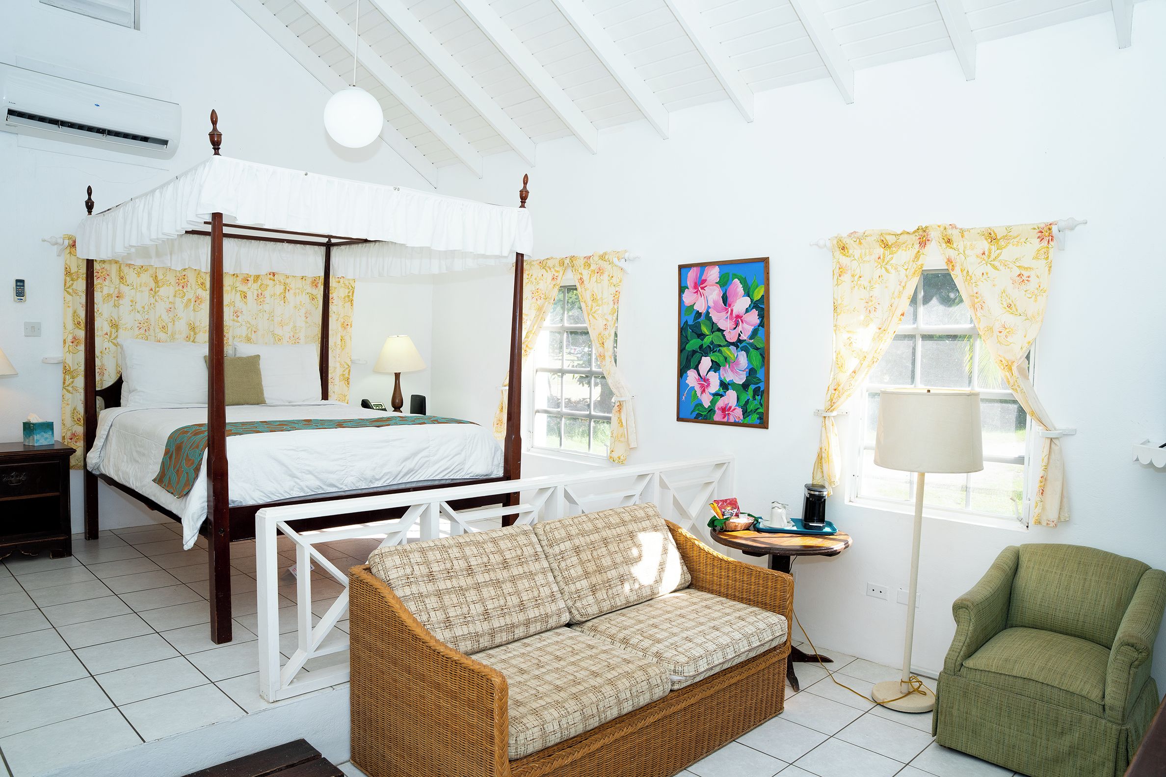 A four-poster bed, a sofa, a chair, a table, and a window with curtains.