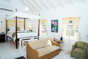 A four-poster bed, a sofa, a chair, a table, and a window with curtains. - Oualie Beach Resort (Newcastle)