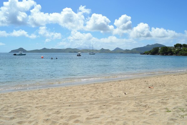 A beach with clear skies, calm water, and boats. - Oualie Beach Resort (Newcastle)