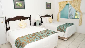 Quarto de hotel com duas camas, uma janela com cortinas e uma porta.