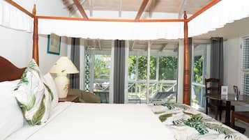Una cama con dosel que ofrece vista a un balcón, una mesa con una lámpara y una silla.