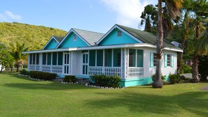 A two-story house with a porch, surrounded by a well-maintained lawn and palm trees.