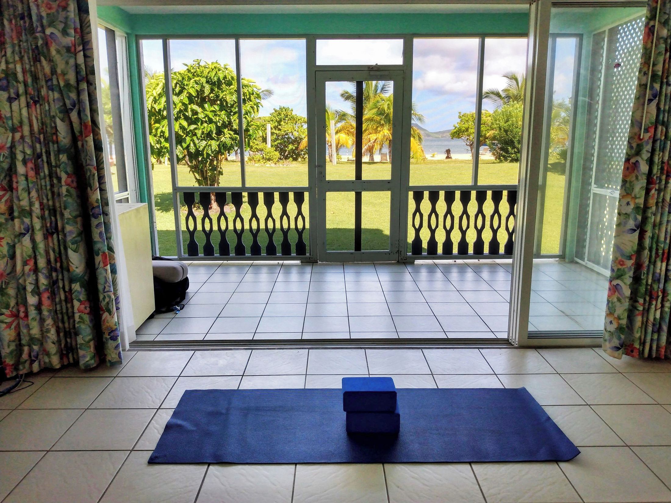 Ein Zimmer mit einer großen Schiebeglasdoor, die auf einen Balkon mit Blick auf eine Wiese und Bäume führt.