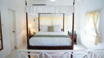 Una camera da letto con un letto a baldacchino, un comodino con una lampada, una finestra con tende e una porta.