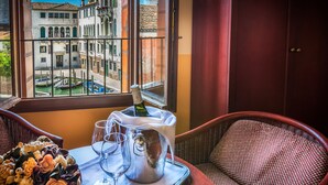Una habitación con vistas a Venecia a través de una ventana, una bandeja con una botella de champán, copas y un ramo de flores.