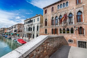 A canal with boats docked, historic buildings with arched windows, and a stone wall. - Palazzo Marcello Hotel al Sole (Venice)