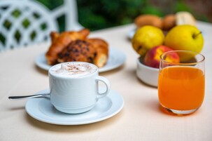 Colazione con una tazza di caffè, un bicchiere di succo d'arancia e un piatto di croissant e frutta.