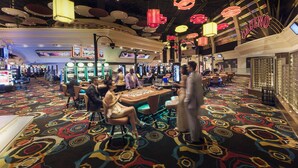 A casino interior with slot machines, a roulette table, and a vibrant carpet pattern. - Sun City Hotel and Casino (Moses Kotane)