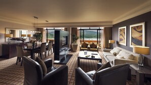 A hotel room with a dining area, a living room with a sofa and coffee table, and a TV. There are large windows with a view of the mountains. - Sun City Hotel and Casino (Moses Kotane)