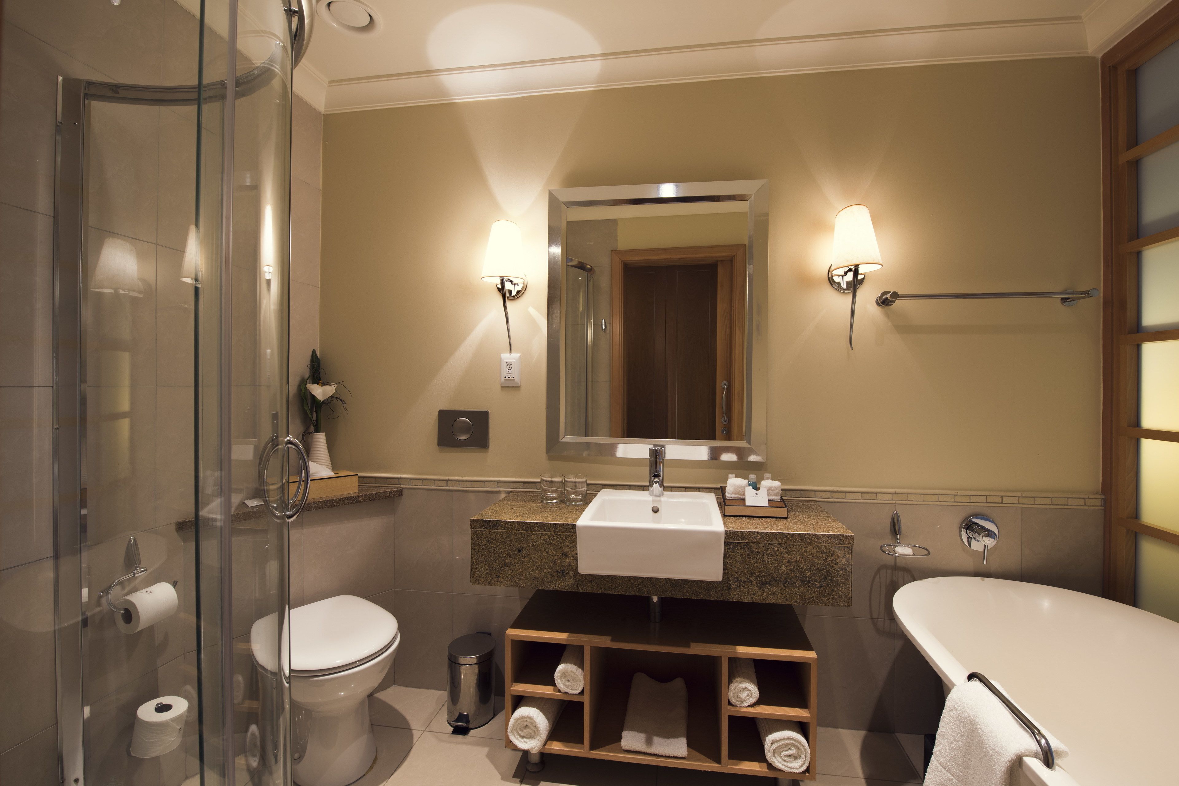 A modern bathroom with a glass shower enclosure, a white toilet, a sink with a mirror above, and a bathtub.
