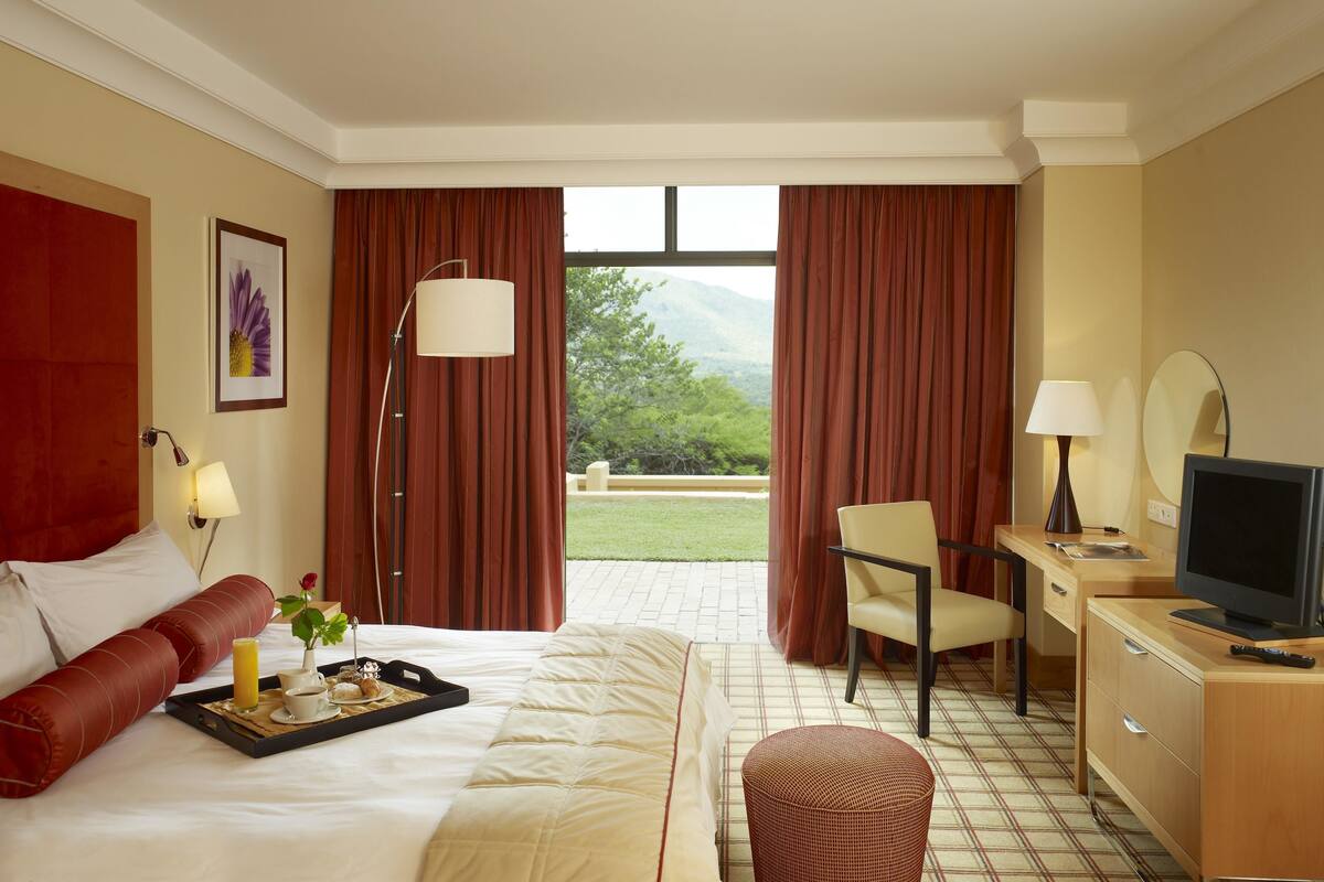 Une chambre d’hôtel équipée d’un lit, d’un bureau, d’une télévision et offrant une vue sur l’extérieur.