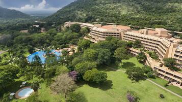 Experience a serene atmosphere amidst lush greenery and a tranquil setting, with a spacious pool area and well-manicured lawns.