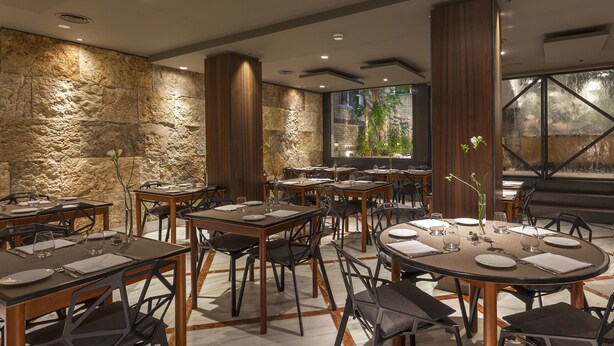 A modern dining area with stone walls, wooden tables, and black chairs. - Hotel Balmes, a member of Preferred Hotels & Resorts (Barcelona)