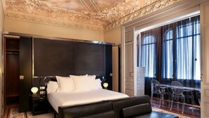 A hotel room with a large bed, a nightstand, a desk with a chair, and a balcony with curtains. - Hotel Balmes, a member of Preferred Hotels & Resorts (Barcelona)