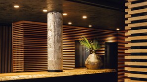 A reception area with a central column, a vase with a plant, and wooden slats on the walls. - Hotel Balmes, a member of Preferred Hotels & Resorts (Barcelona)