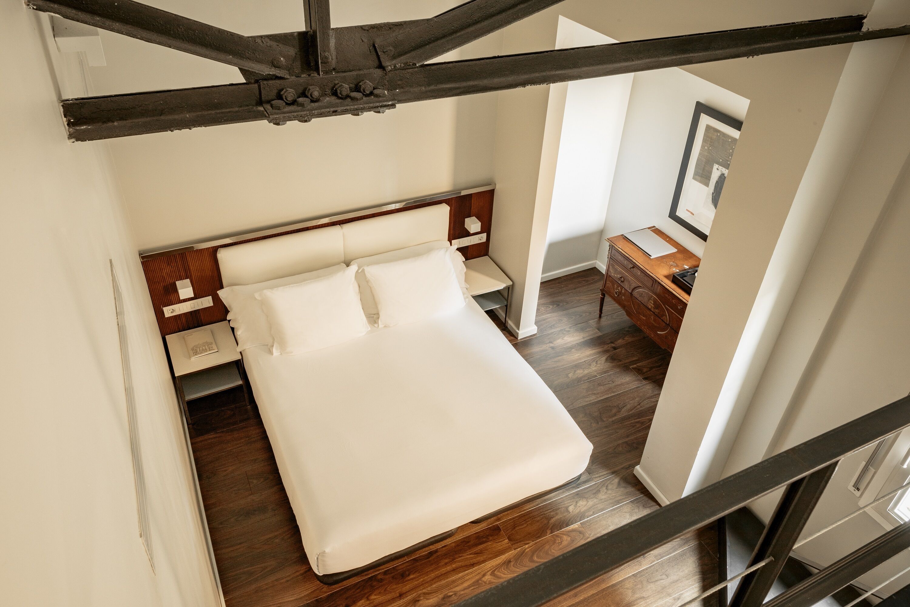 Une chambre à coucher avec un lit, une tête de lit en bois, des tables de chevet et une commode.