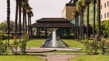 A courtyard with a fountain, palm trees, and a building with a modern design.