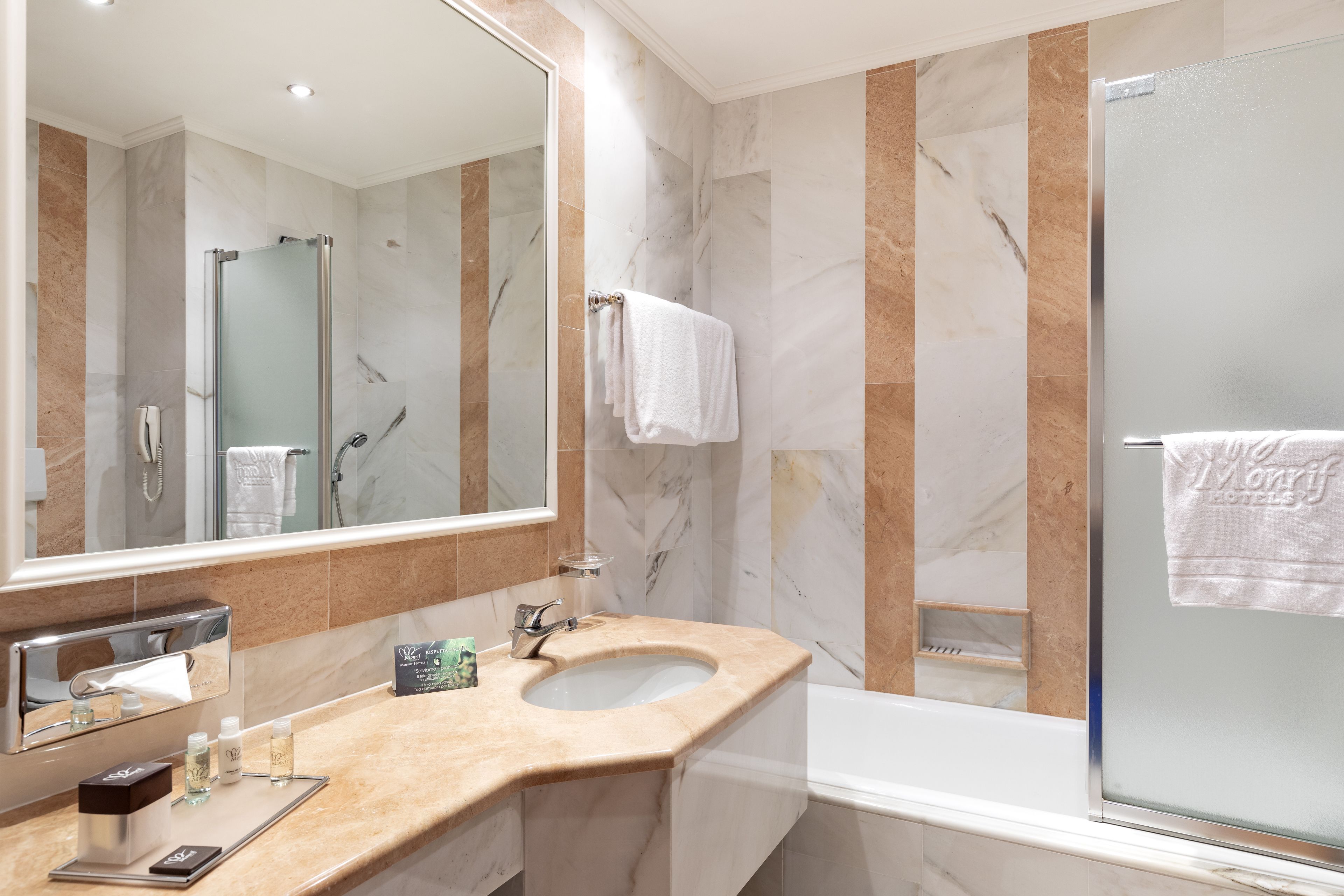 A modern bathroom with a marble vanity, a glass-enclosed shower, and a large mirror.