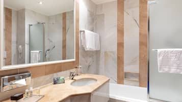 A modern bathroom with a marble vanity, a glass-enclosed shower, and a large mirror.