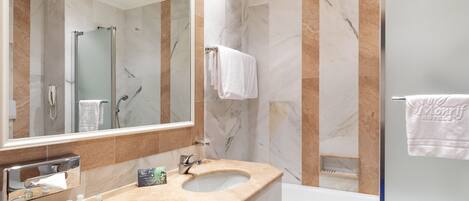 Un baño moderno con tocador de mármol, ducha con cerramiento de vidrio y un espejo grande.