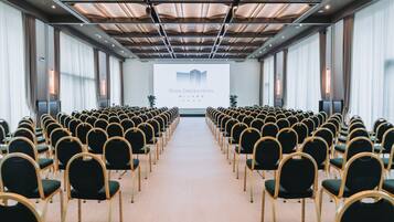 A conference room with rows of chairs facing a projection screen displaying the Royal Garden Hotel Milano logo.