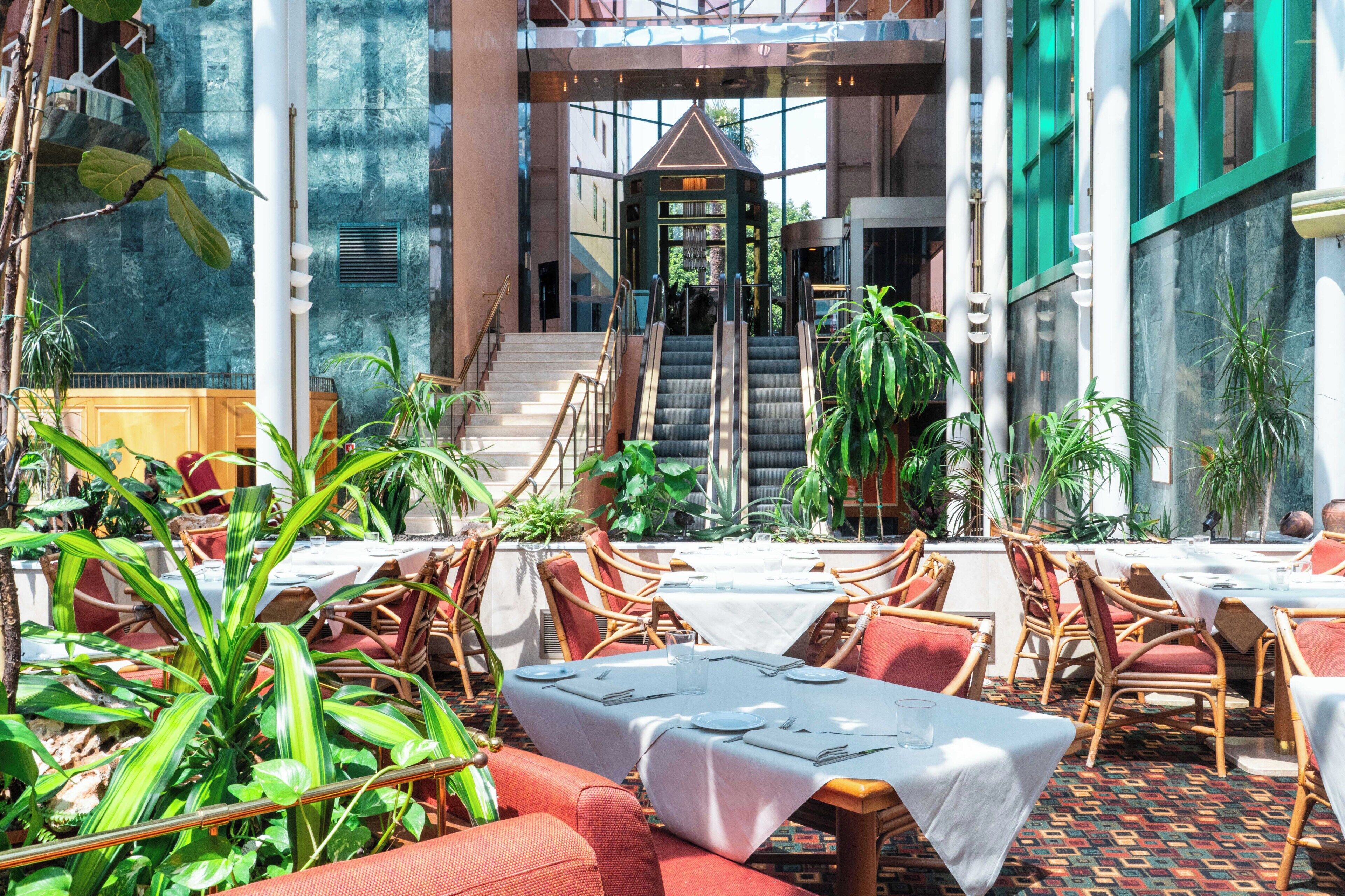 An indoor dining area with tables, chairs, and a staircase leading to an upper level.