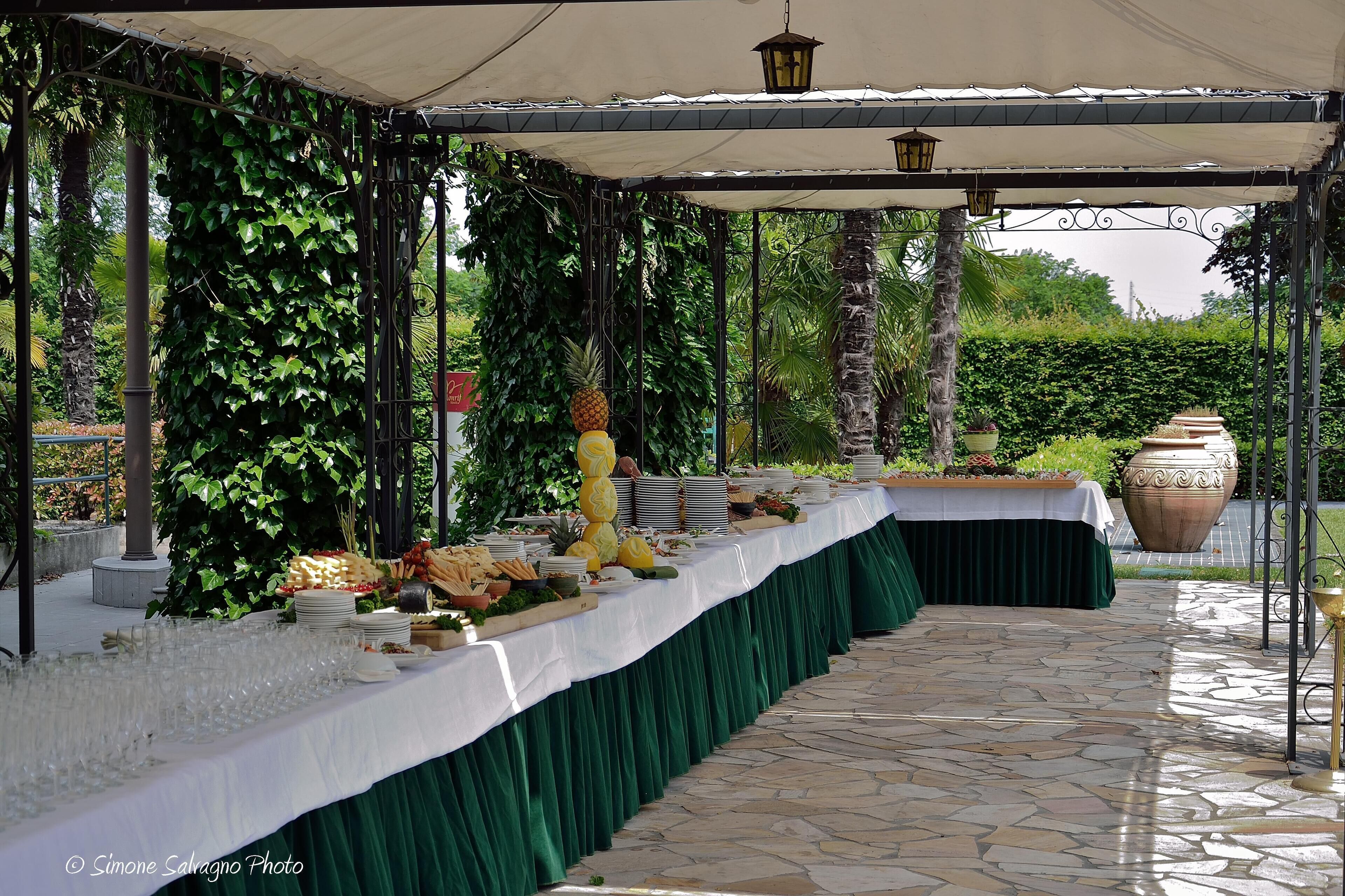 Un área de comedor al aire libre con una mesa cubierta, puesta con platos, vasos y comida.