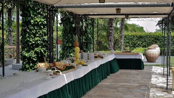 Un área de comedor al aire libre con una mesa cubierta, puesta con platos, vasos y comida.