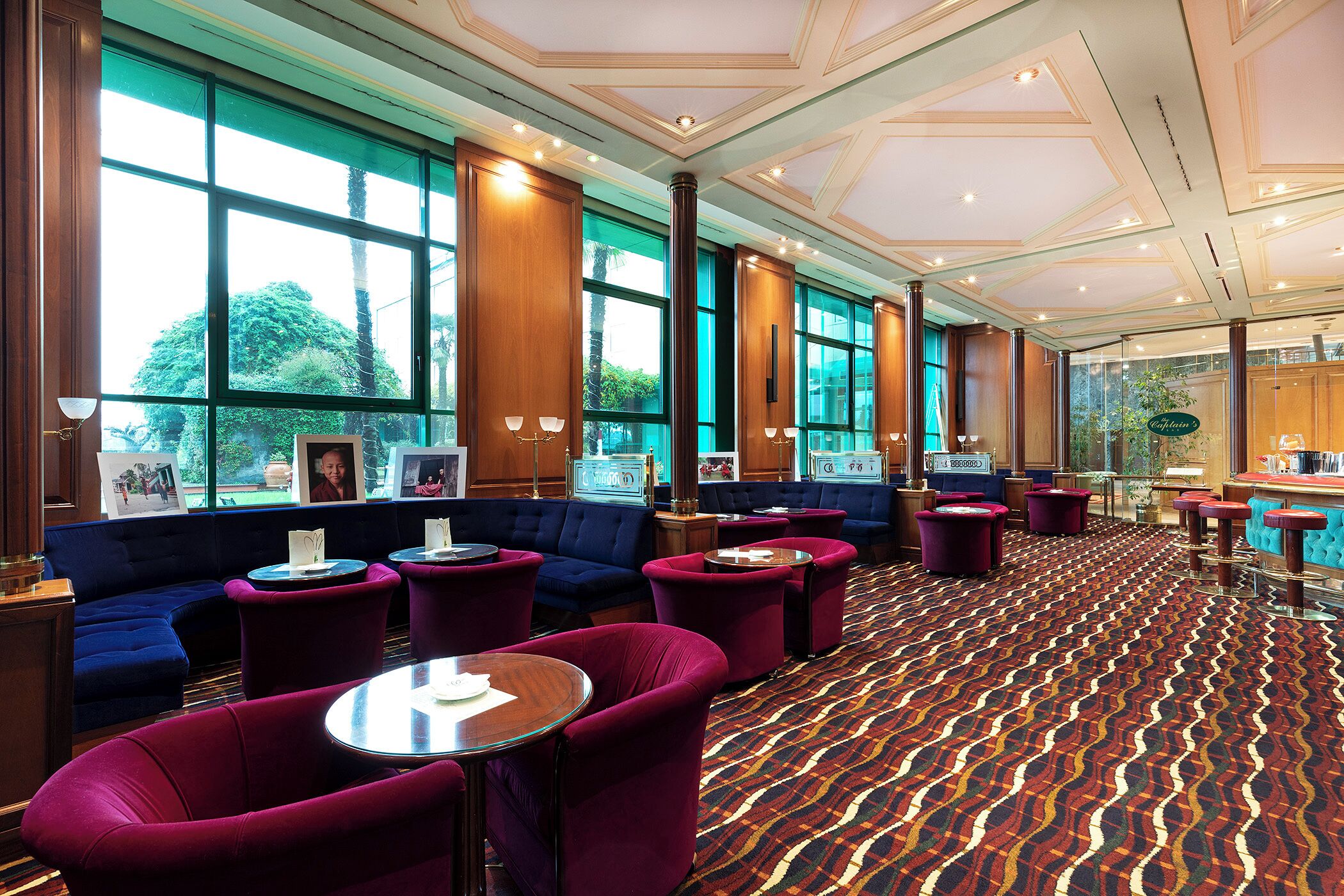 Een hotel lobby met zithoeken, grote ramen en een kamerbreed tapijt.