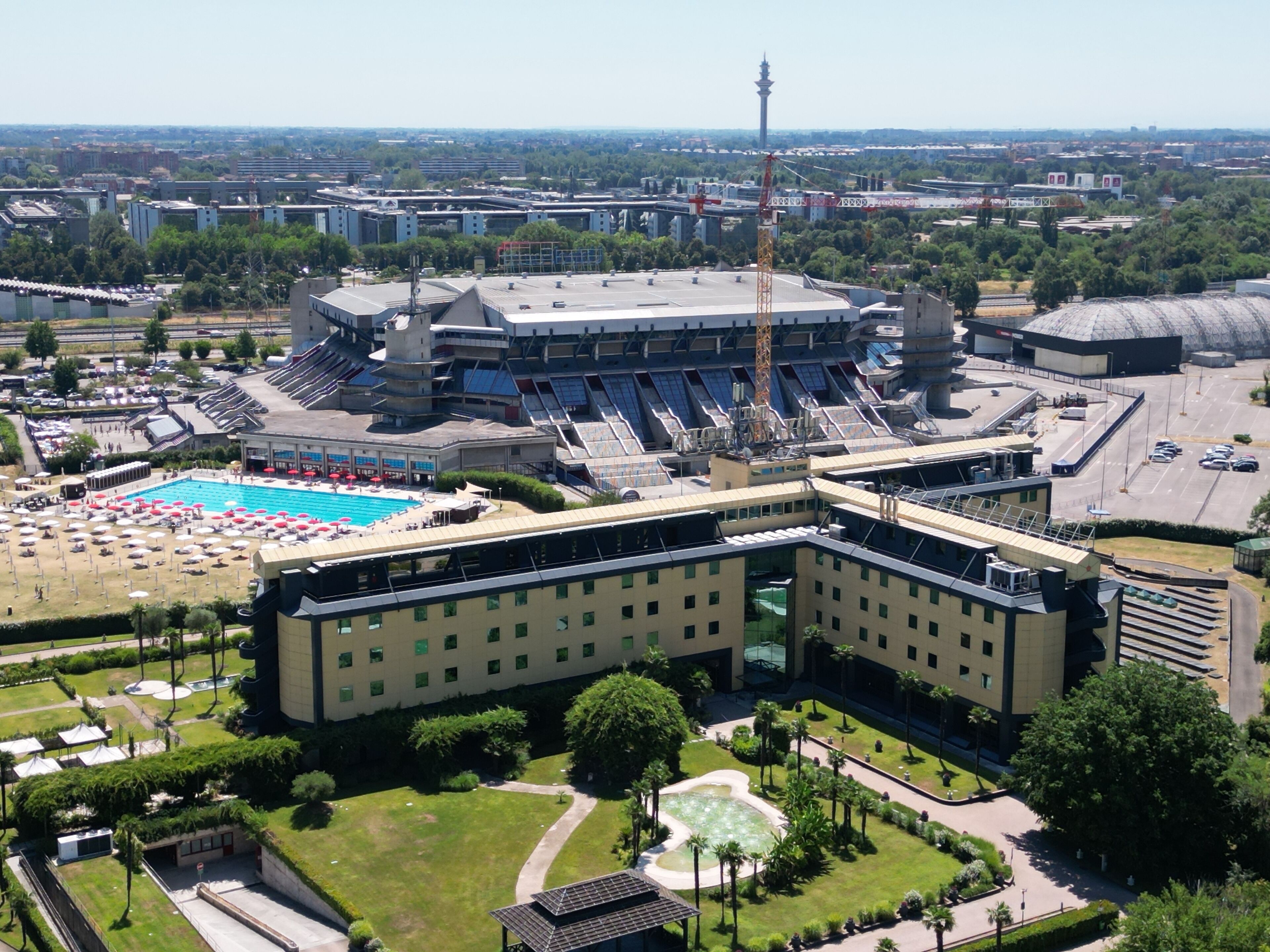 A large building with a swimming pool, multiple floors, and a tower.