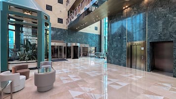 A spacious lobby with a high ceiling, marble flooring, and modern furniture.