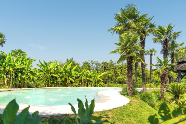 A pool surrounded by lush greenery and palm trees. - Royal Garden Hotel (Assago)