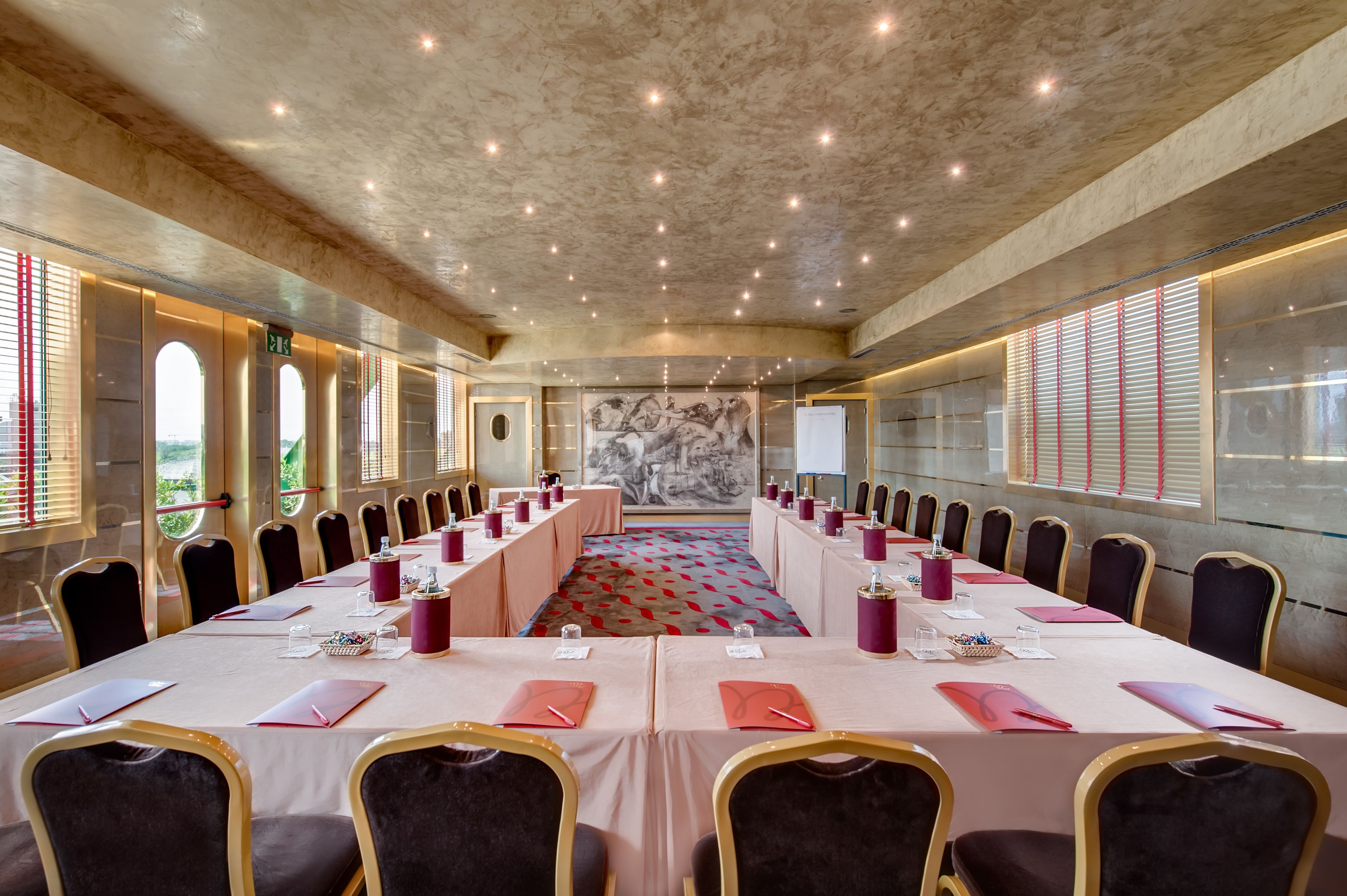 Un salón de conferencias con una larga mesa, sillas y un mural en la pared.