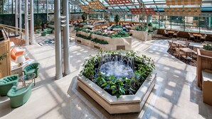 Un amplio atrium con una fuente central, zonas de estar y un techo de cristal que deja entrar luz natural.