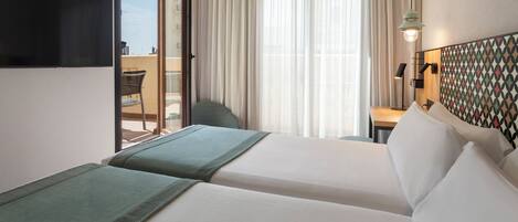 A hotel room with two beds, a desk, a chair, and a view of the outdoors.