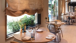 Comedor con mesas redondas, sillas y vistas a zonas verdes.
