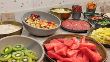 Una encimera de cocina con diversos alimentos, entre ellos frutas, verduras y carne.