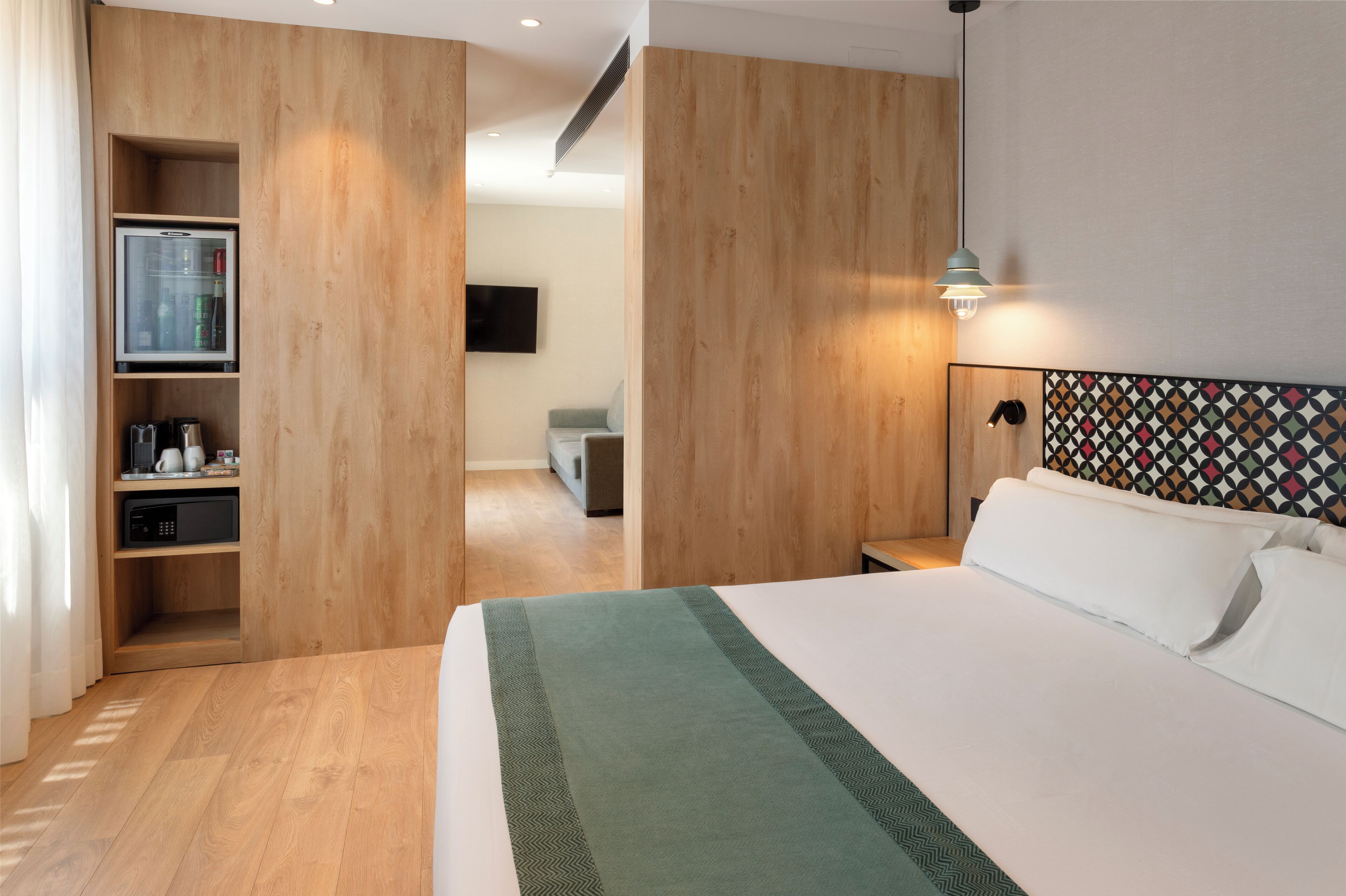 Una habitación de hotel moderna con una cama grande, paneles de madera, un televisor y un microondas.