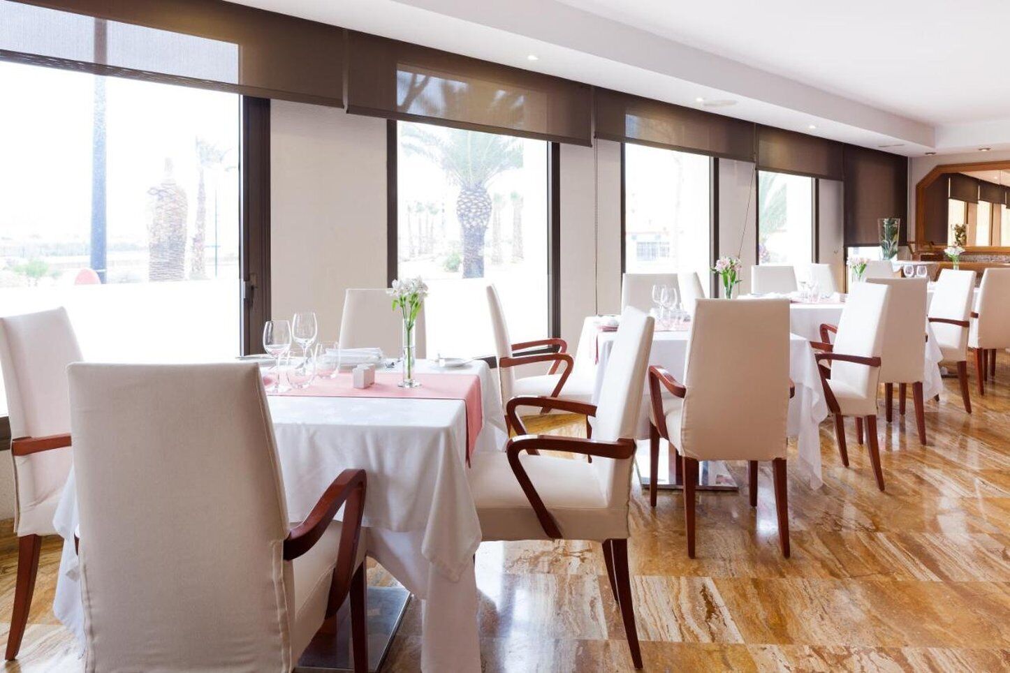 Un restaurant avec plusieurs tables, des chaises blanches et un plancher en bois.