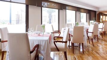 Un restaurant avec plusieurs tables, des chaises blanches et un plancher en bois.