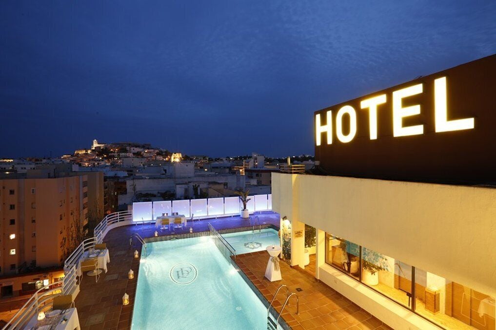 Un hotel con piscina en la azotea, vistas de la ciudad y un cartel llamativo que dice 'HOTEL'.