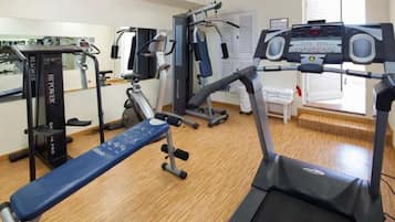 Un gimnasio con diversos equipos de ejercicio, incluyendo cinta de correr, elíptica y máquinas de pesas.
