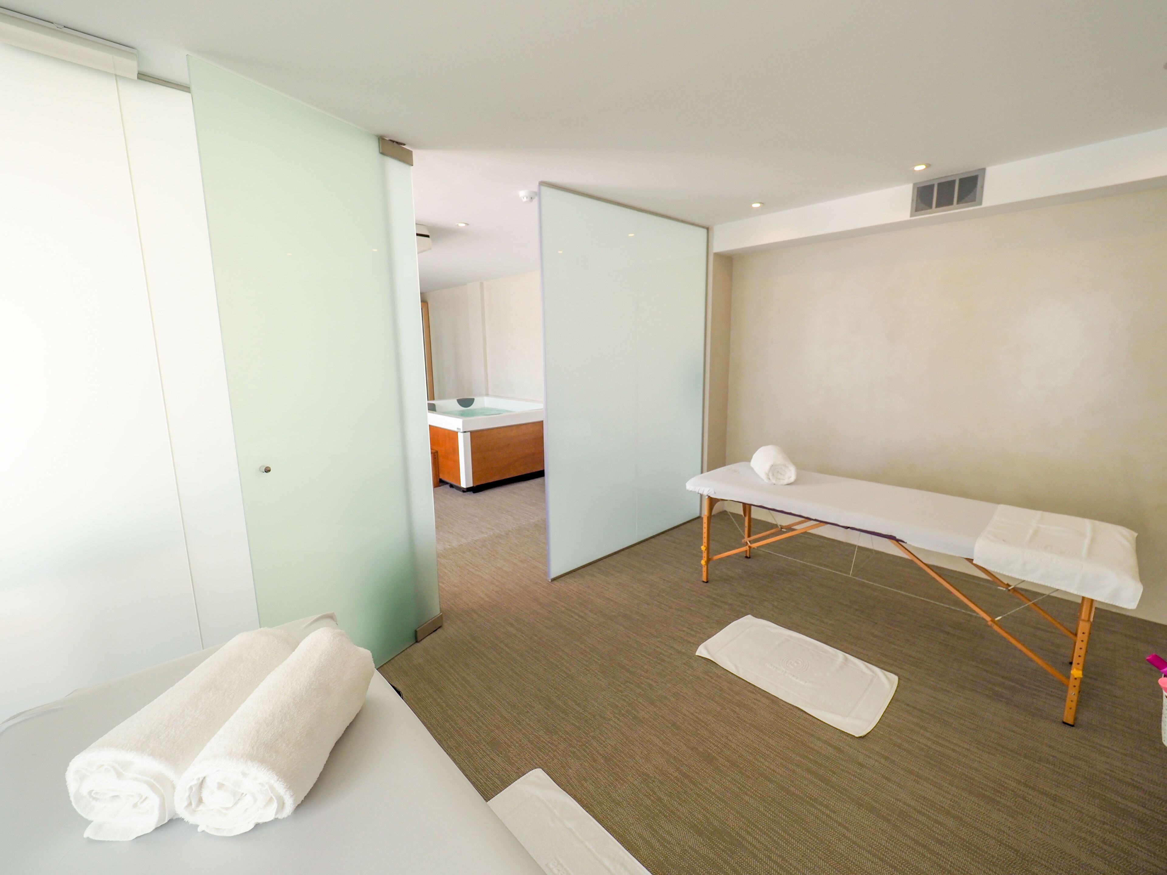 Une salle de spa moderne équipée d’une table de massage, de deux serviettes et d’un plancher en bois.