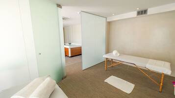 Une salle de spa moderne équipée d’une table de massage, de deux serviettes et d’un plancher en bois.